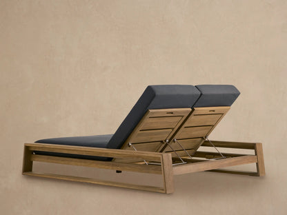 Close-up of Canyon Outdoor Teak Double Chaise showing raised, slatted teak wood back and dark grey cushion, with adjustable metal bars visible.