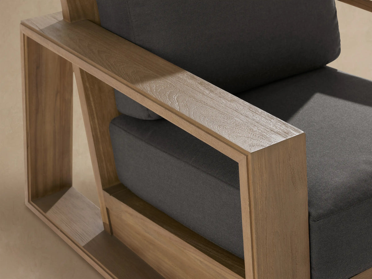 Front view of Canyon Outdoor Teak Swivel Chair, natural light brown teak frame with visible wood grain, dark grey cushions.