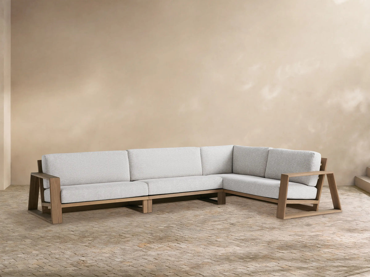 Canyon Outdoor Teak Three-Piece Sectional, L-shaped, with light grey cushions & natural teak wood frame, on a patio.