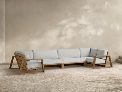 L-shaped Canyon Outdoor Teak Four-Piece Sectional with light grey cushions, open geometric frame, on a stone patio.