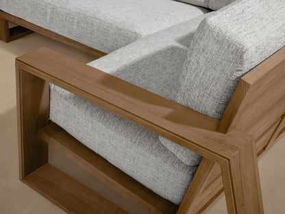Canyon Outdoor Teak Four-Piece Sectional: L-shaped configuration with natural wood frame & light grey cushions on a stone patio.