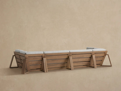 Close-up of Canyon Outdoor Teak Sectional corner. Features warm brown teak frame with light grey textured cushions.