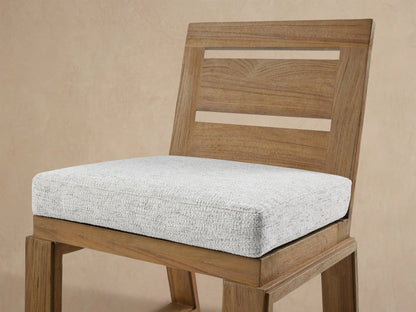 Front view of Canyon Outdoor Teak Dining Side Chair. Natural teak wood frame with two back slats and a light grey fabric seat cushion.