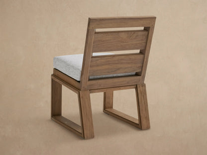 Canyon Outdoor Teak Dining Side Chair with warm brown, textured teak frame, slatted backrest, and light grey fabric cushion.