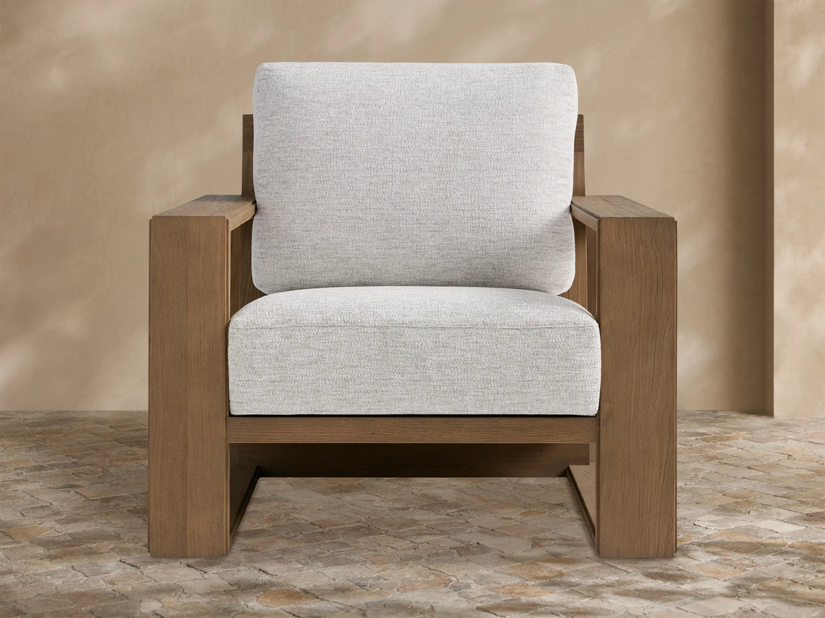 Canyon Outdoor Teak Lounge Chair with a modern geometric teak wood frame and light gray cushions on a stone patio.