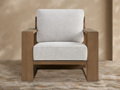 Canyon Outdoor Teak Lounge Chair with a modern geometric teak wood frame and light gray cushions on a stone patio.
