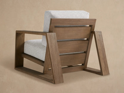 Close-up of the Canyon Outdoor Teak Lounge Chair's angular brown teak armrest and light grey textured cushions.