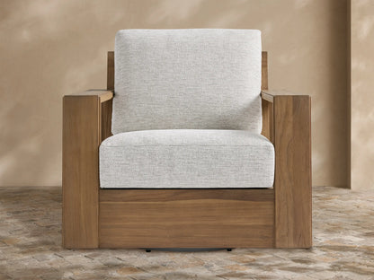 Canyon Outdoor Teak Swivel Chair with golden-brown teak frame & light gray cushions, angled on a rustic tiled patio.