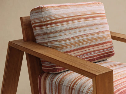 Front view of Canyon Outdoor Teak Lounge Chair with natural teak wood frame and striped cushions in red, orange, beige, light blue, and white.