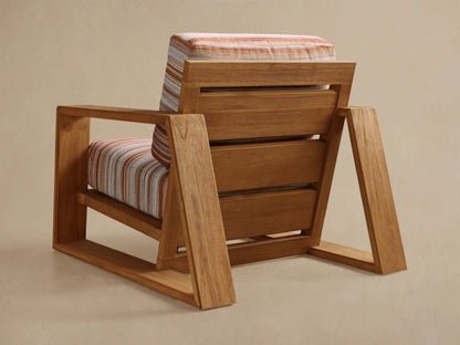 Close-up, angled view of the Canyon Outdoor Teak Lounge Chair, with a warm brown teak frame and striped cushions in orange, cream, and gray.