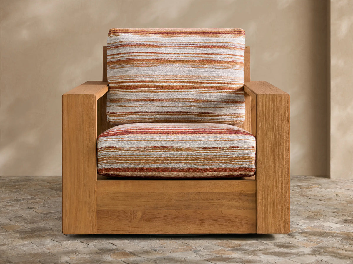 Canyon Outdoor Teak Swivel Chair, angled front-right, with warm brown teak frame and striped orange/white/red cushions on a patio.