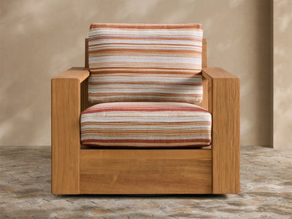 Canyon Outdoor Teak Swivel Chair, angled front-right, with warm brown teak frame and striped orange/white/red cushions on a patio.