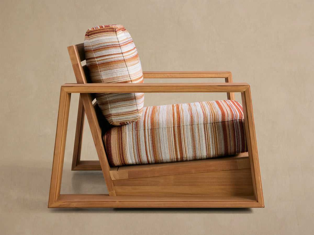 Canyon Outdoor Teak Swivel Chair, angled back view. Honey teak frame, slatted back, with striped orange, white, and beige cushions.