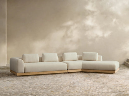 Light cream Carmel Outdoor Two-Piece Bumper Sectional, L-shaped with teak base, lumbar pillows, on a tiled patio.