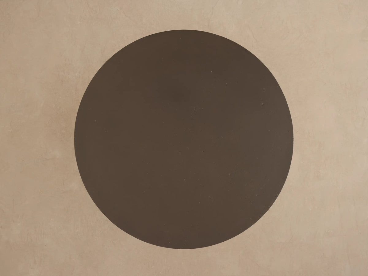 Two dark brown Cascade Outdoor Coffee Tables, round tops with column legs. Larger table behind smaller one on light beige.