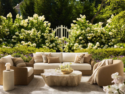 Clayhill Outdoor Coffee Table, light beige, with a rugged, tree-trunk-like fiberglass base and irregular, textured tabletop.