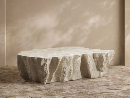 Clayhill Outdoor Coffee Table with a light, organic, tree trunk-like design, centered in an outdoor patio seating area with lush plants.
