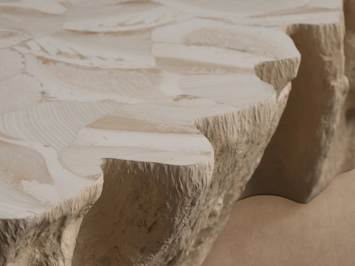 Clayhill Outdoor Coffee Table, light beige, with an organic, rough rock-like texture and irregular shape, on a tiled floor.