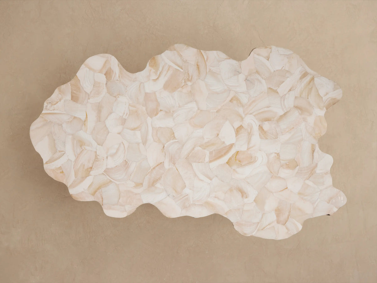 Close-up of Clayhill Outdoor Coffee Table: polished light shell-like mosaic top with organic edge, textured light brown trunk-like base.