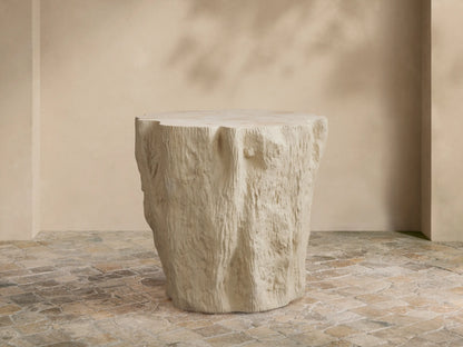 Clayhill Outdoor Tapered End Table, light beige, textured tree stump design, on a patterned stone patio floor.