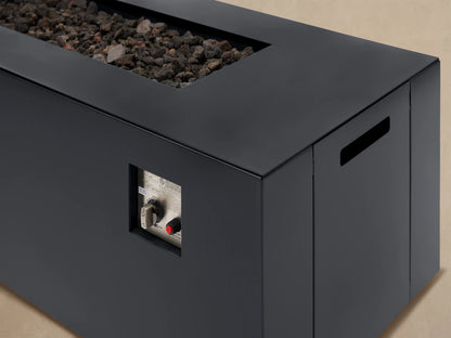Dark gray Coden Rectangular Propane Fire Pit with lava rocks on a light patio, positioned against a wooden shingle wall.