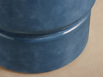 Colorno Outdoor End Table, cylindrical, mottled blue, glossy finish, with recessed base on stone floor against beige wall.