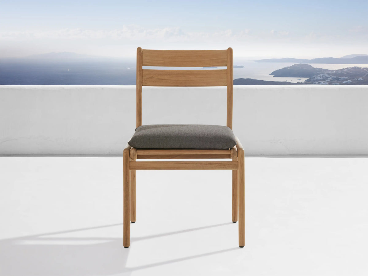 A light gray protective cover from the Del Ray Outdoor Collection snugly fits over a chair. The background shows a scenic ocean view.
