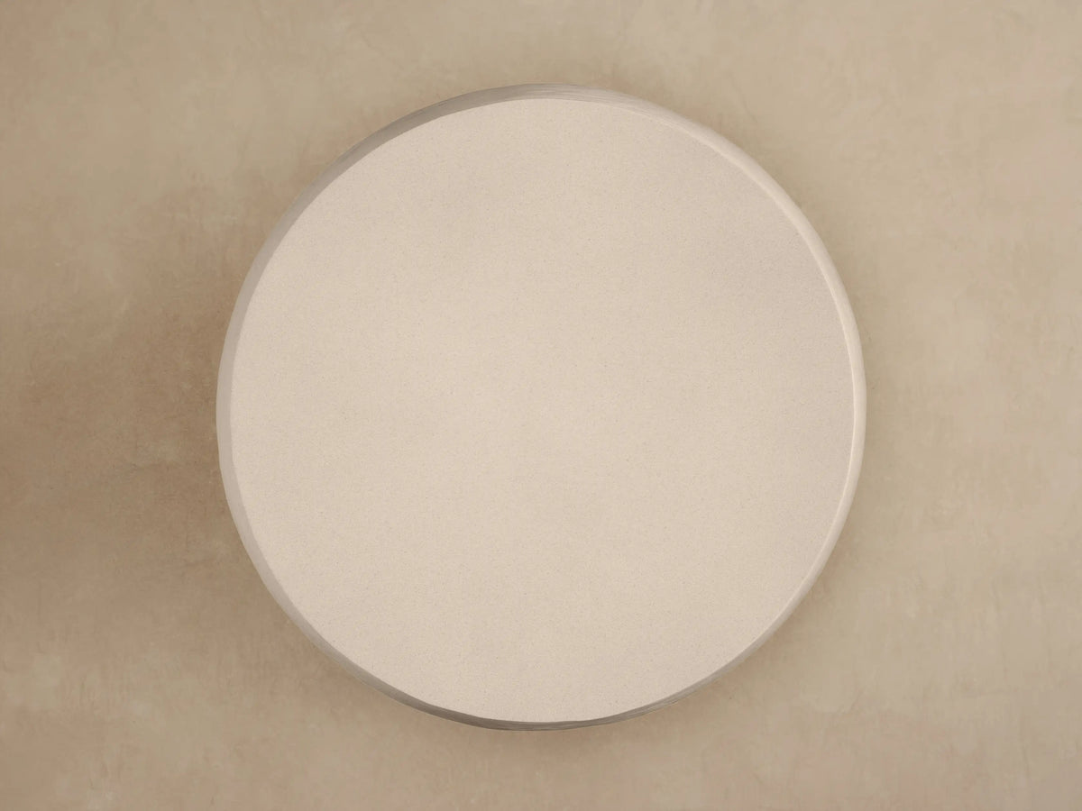 Close-up of Eden Outdoor Round Coffee Table, light beige, with smooth top surface & horizontally ribbed, textured sides.