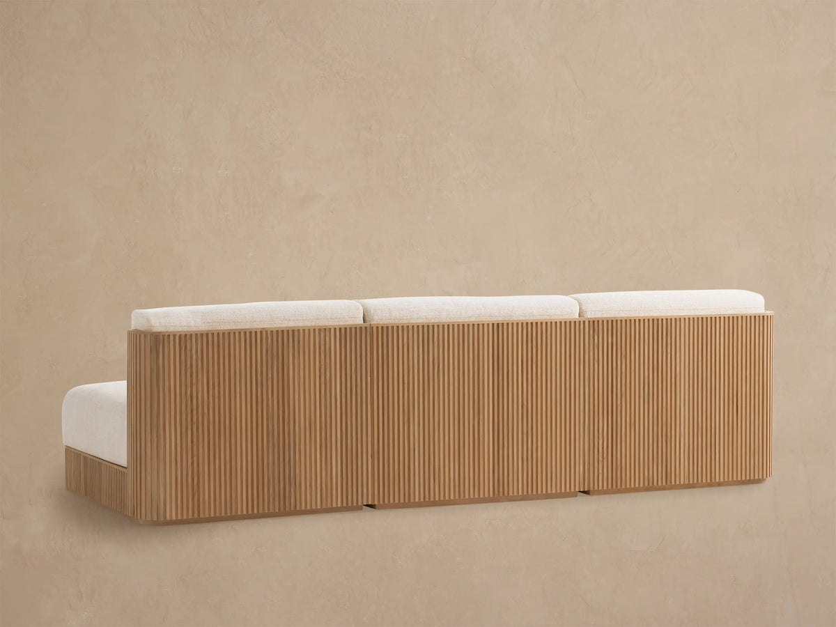 Close-up of Beaumont modular sofa with natural slatted teak armrest and light beige textured outdoor fabric cushions, angled view.