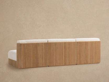 Close-up of Beaumont modular sofa with natural slatted teak armrest and light beige textured outdoor fabric cushions, angled view.