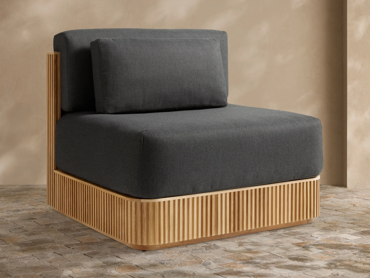 Beaumont Outdoor Teak Lounge Chair in Rosemount Graphite. Front-right view of dark grey cushions on a slatted light teak wood base.