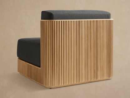 Close-up of Beaumont Outdoor Teak Lounge Chair. Light teak frame with vertical slats, dark grey Rosemount Graphite cushions, angled view.