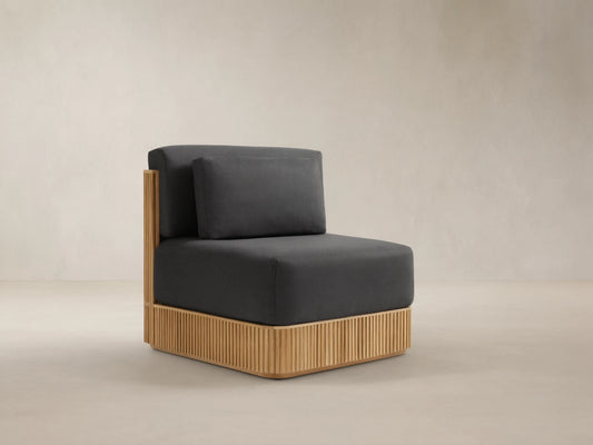 Beaumont Outdoor Teak Lounge Chair in Rosemount Graphite. Front-right view of dark grey cushions on a slatted light teak wood base.