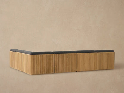 Close-up of Beaumont Outdoor Teak Sectional corner with natural slatted frame and dark grey cushions, viewed from above.