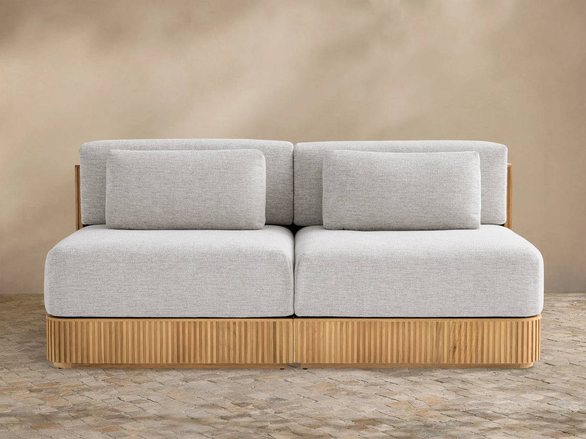 Beaumont Outdoor Teak Two-Piece Modular Sofa with light gray cushions on a natural teak wood base with vertical slats.