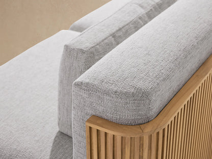Beaumont Outdoor Teak Two-Piece Modular Sofa. Light grey cushions on natural teak base with vertical grooves, angled view.