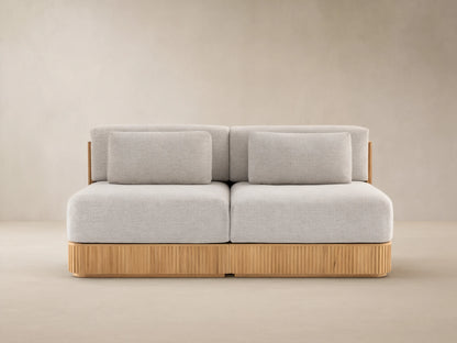 Beaumont Outdoor Teak Two-Piece Modular Sofa with light gray cushions on a natural teak wood base with vertical slats.