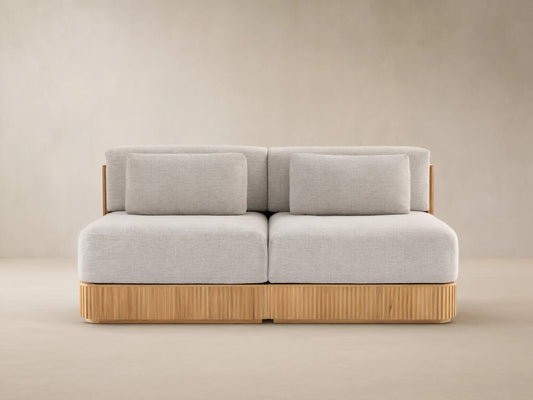 Beaumont Outdoor Teak Two-Piece Modular Sofa with light gray cushions on a natural teak wood base with vertical slats.