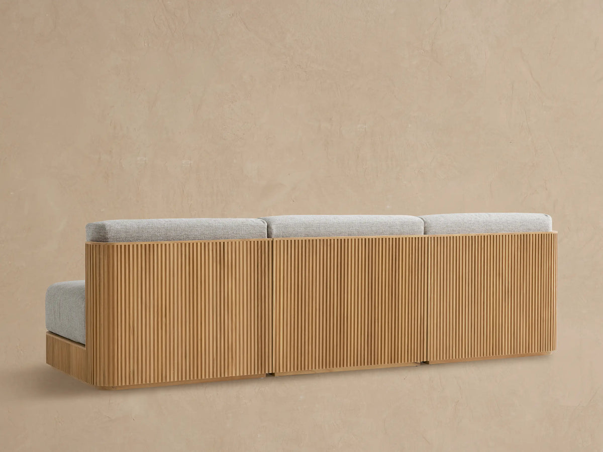 Close-up of Beaumont Outdoor Teak Modular Sofa showing light grey textured cushions and natural slatted teak wood side panel.