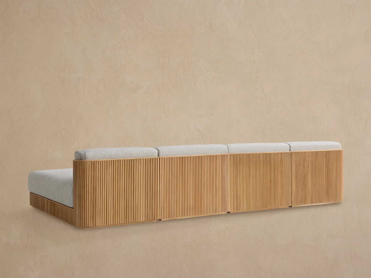Close-up of Beaumont Outdoor Sectional's slatted natural teak wood side arm meeting light gray textured seat and back cushions.