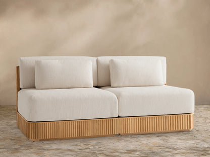 Beaumont Outdoor Teak Two-Piece Modular Sofa, front view. Light beige cushions on slatted natural teak wood base.