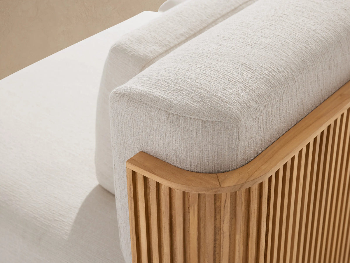 Beaumont Outdoor Teak Two-Piece Modular Sofa with cream cushions and a natural teak wood slatted base, against a beige wall.