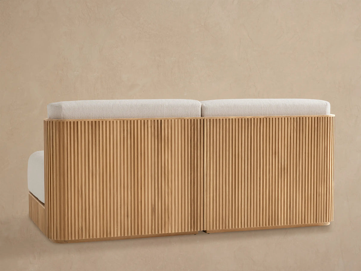 High-angle close-up of Beaumont Modular Sofa corner. Cream textured cushion meets slatted natural teak frame.