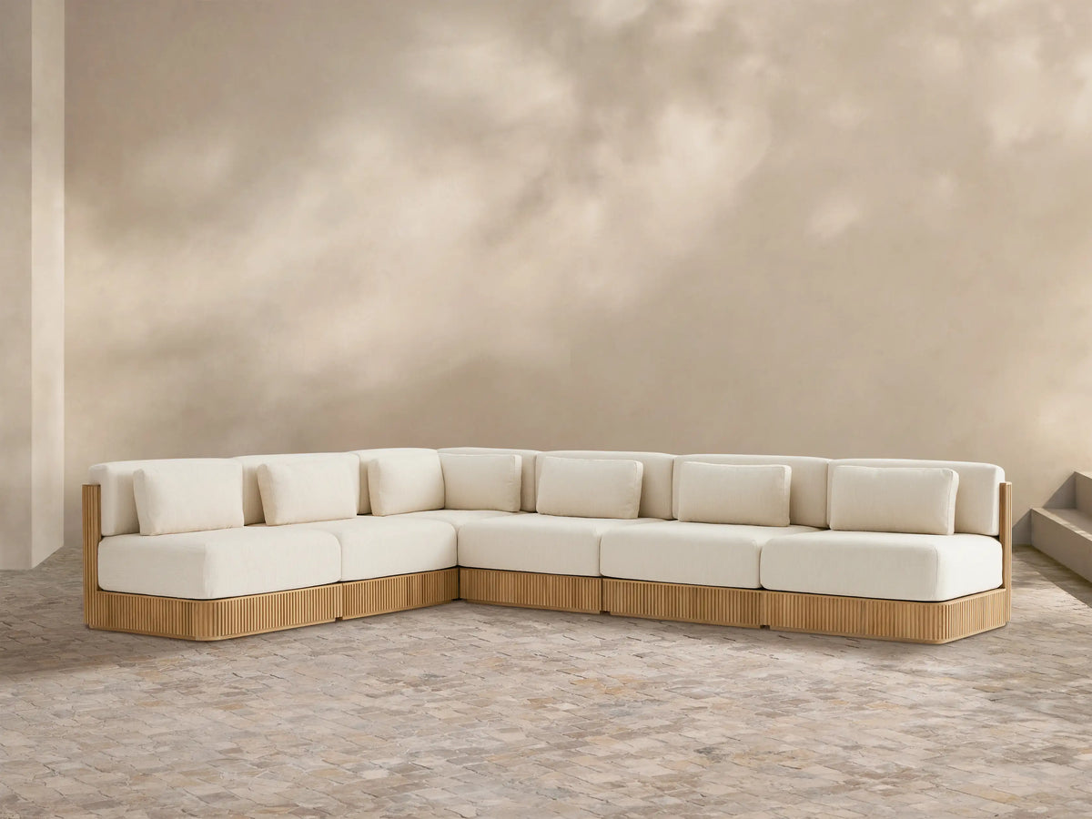 L-shaped Beaumont Outdoor Teak Six-Piece Sectional with grooved teak base & cream cushions on a tiled patio.