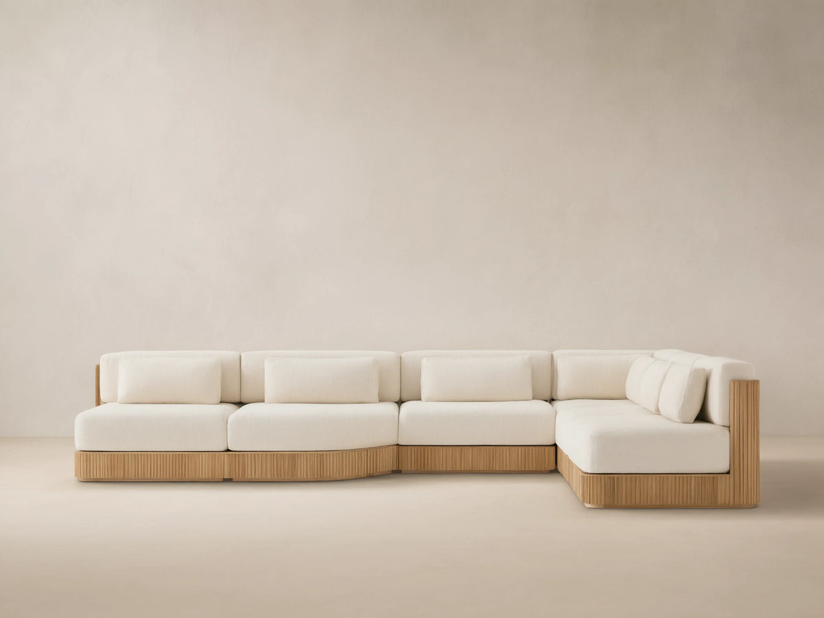 L-shaped Beaumont Outdoor Teak Six-Piece Sectional with grooved teak base & cream cushions on a tiled patio.