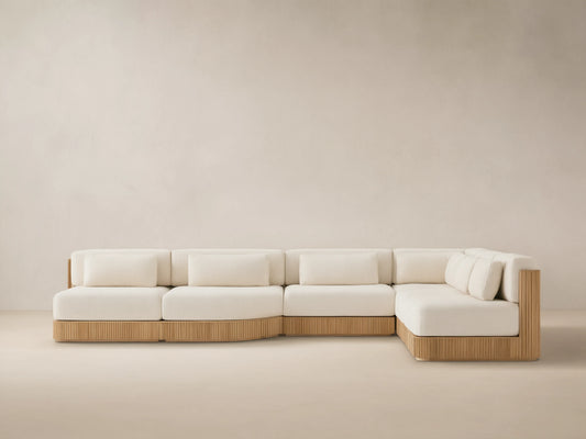 L-shaped Beaumont Outdoor Teak Six-Piece Sectional with grooved teak base & cream cushions on a tiled patio.