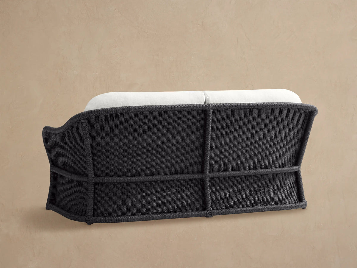 Dark grey woven all-weather wicker frame and white cushion of the Fowler Outdoor Sofa, viewed closely from the back side.