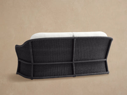 Dark grey woven all-weather wicker frame and white cushion of the Fowler Outdoor Sofa, viewed closely from the back side.