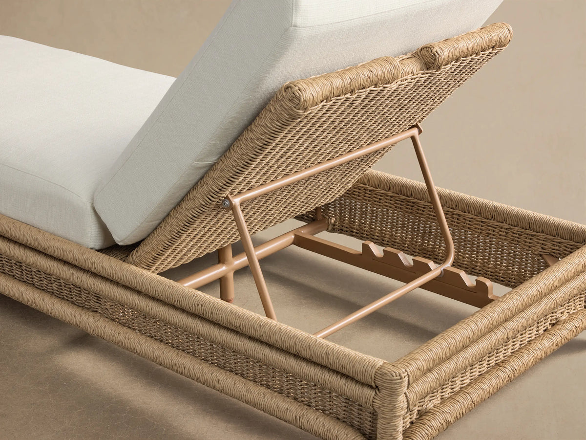 Fowler Outdoor Chaise, side view. Light brown handwoven all-weather wicker base with inclined cream cushions.