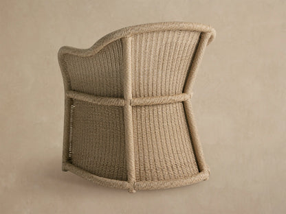 Close-up of Fowler Outdoor Dining Chair, natural woven wicker with braided trim, and a white, textured seat cushion.